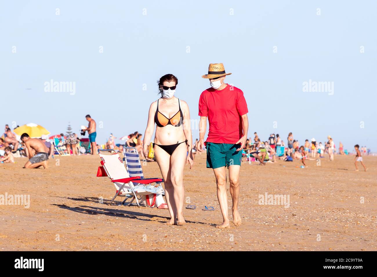 Punta Umbria, Huelva, Espagne - 2 août 2020 : couple marchant sur la plage avec des masques protecteurs ou médicaux. Nouvelle normale en Espagne avec di social Banque D'Images