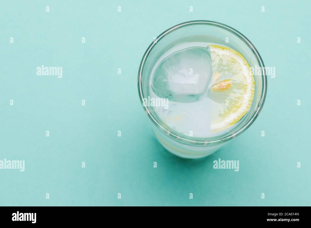 Cocktail avec glace et tranche de citron sur fond bleu vif Banque D'Images