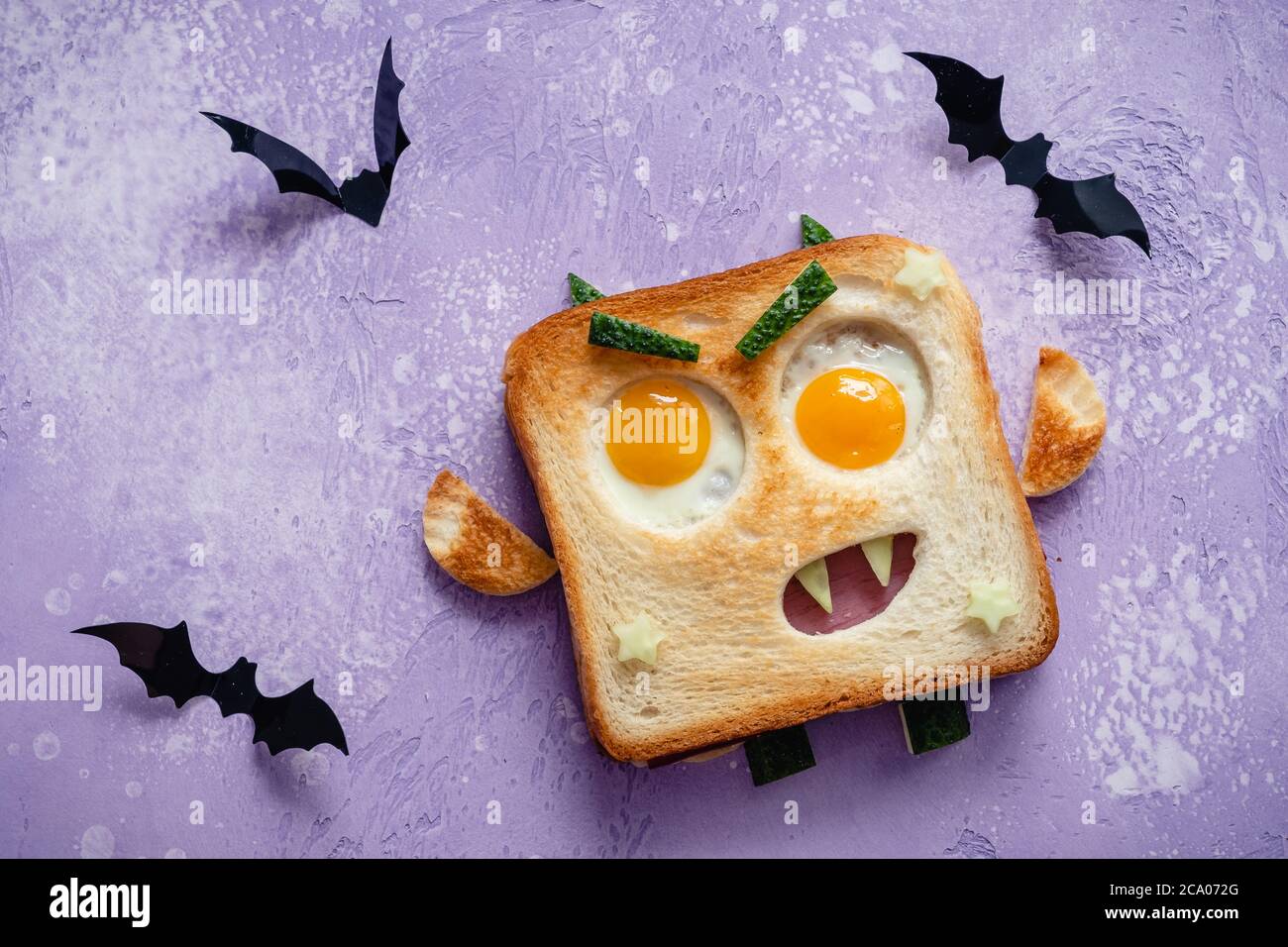Sandwich Halloween monstre amusant avec tranche de saucisse de viande, œufs et fromage sur plaque Banque D'Images