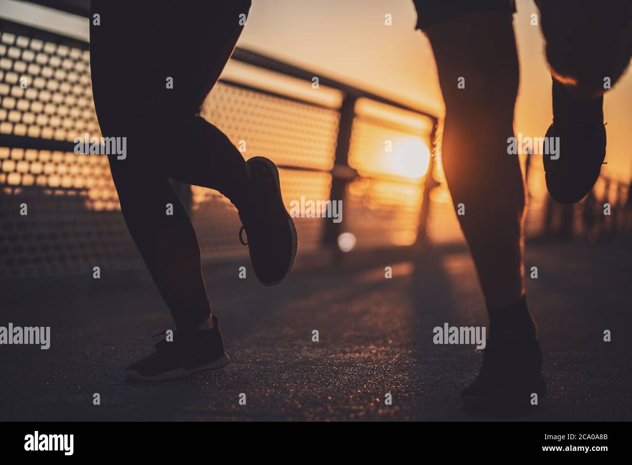 Corps partie silhouettes de couple qui fait du jogging dans la ville au coucher du soleil. Banque D'Images