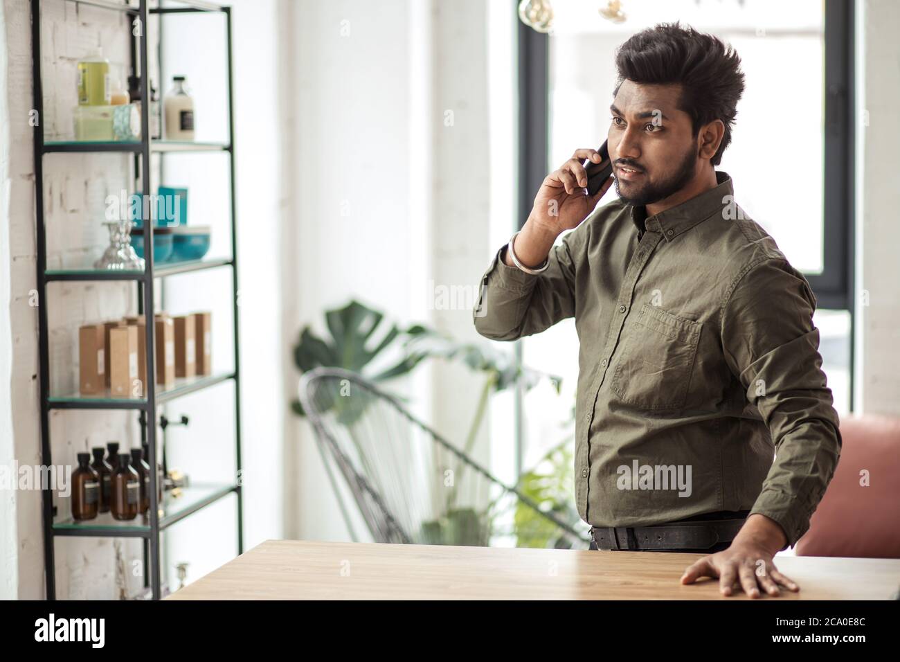 Homme d'affaires indien parlant au téléphone dans un bureau moderne Banque D'Images