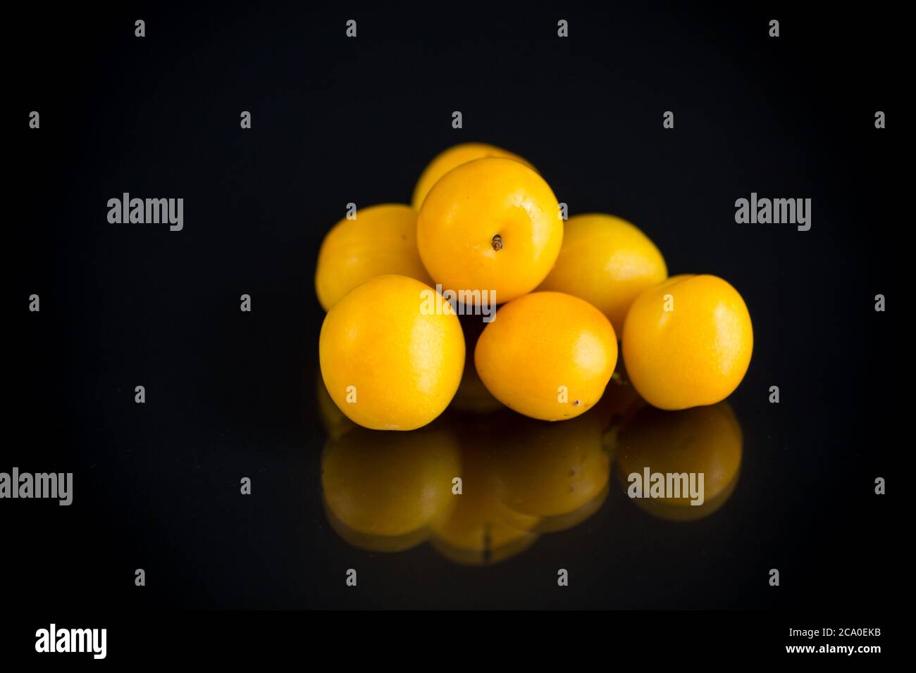 prunes de cerise jaune isolées sur fond noir Banque D'Images
