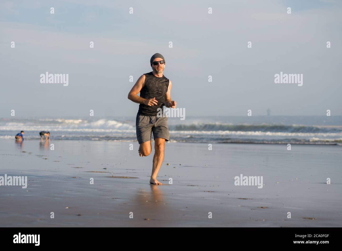 Entraînement de course à pied en plein air - jeune homme coureur attrayant et athlétique jogging sur la belle plage en été entraînement heureux et gratuit dans la forme physique et la santé Banque D'Images
