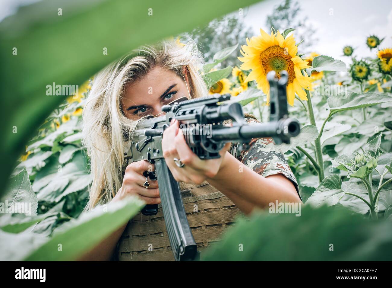 Belle et attrayante femme soldat avec mitraillette à fusil. Point de vue de face du canon. Femme armée nature entraînement militaire de combat en plein air. Femme fatale Banque D'Images