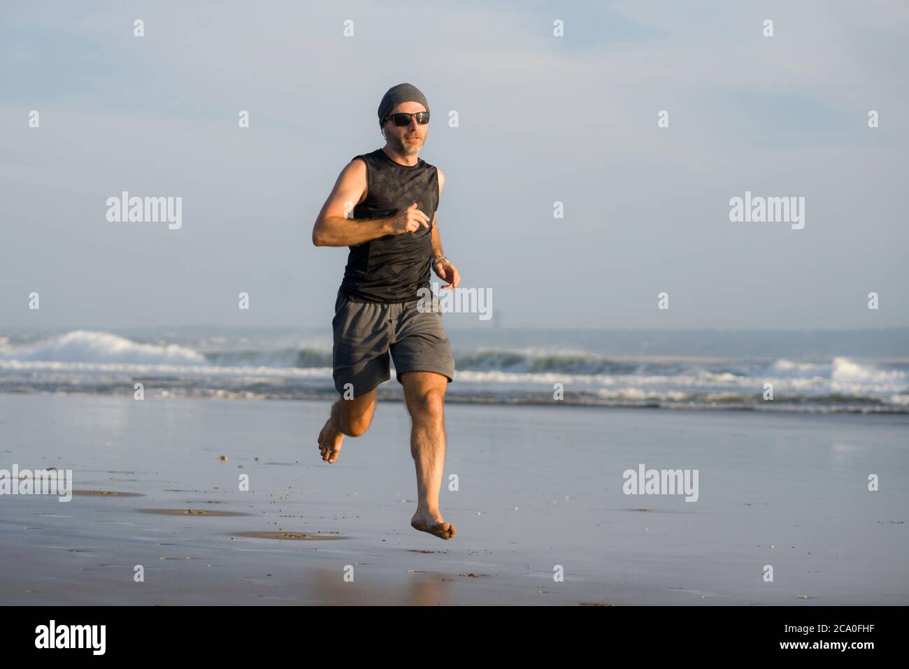 Entraînement de course à pied en plein air - jeune homme coureur attrayant et athlétique jogging sur la belle plage en été entraînement heureux et gratuit dans la forme physique et la santé Banque D'Images