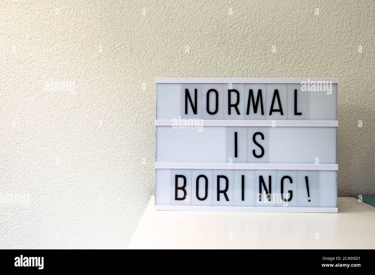 Normal est ennuyeux écrit dans la décoration de la maison de boîte de lumière, signe de motivation maison rétro, espace pour le texte Banque D'Images