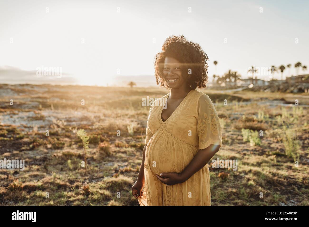 Portrait de la mère enceinte au troisième trimestre à la plage à coucher de soleil Banque D'Images