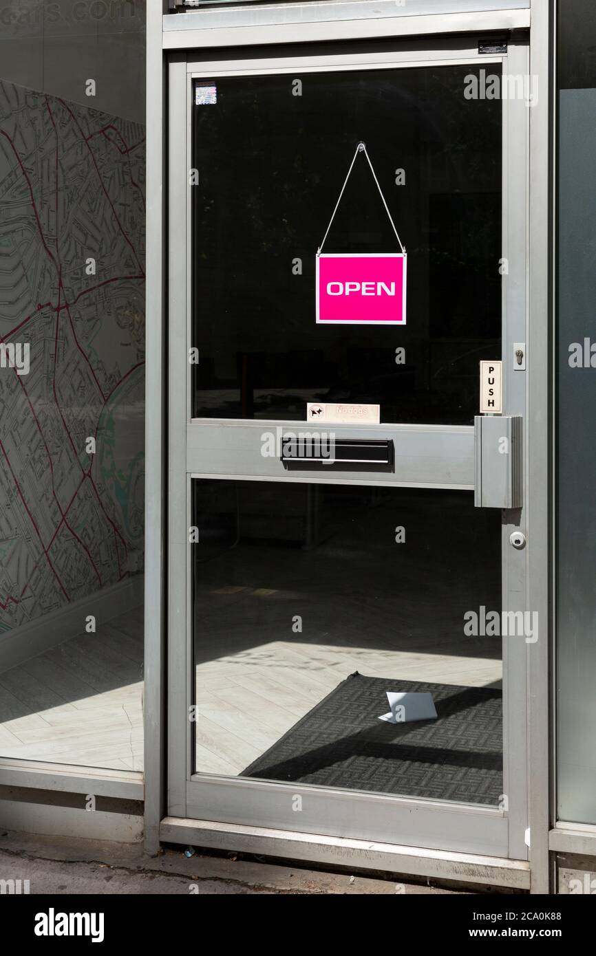 Une porte à un magasin avec un panneau ouvert et un courrier non lu sur le tapis de porte, Harrow Road, Maida Hill, Londres Banque D'Images