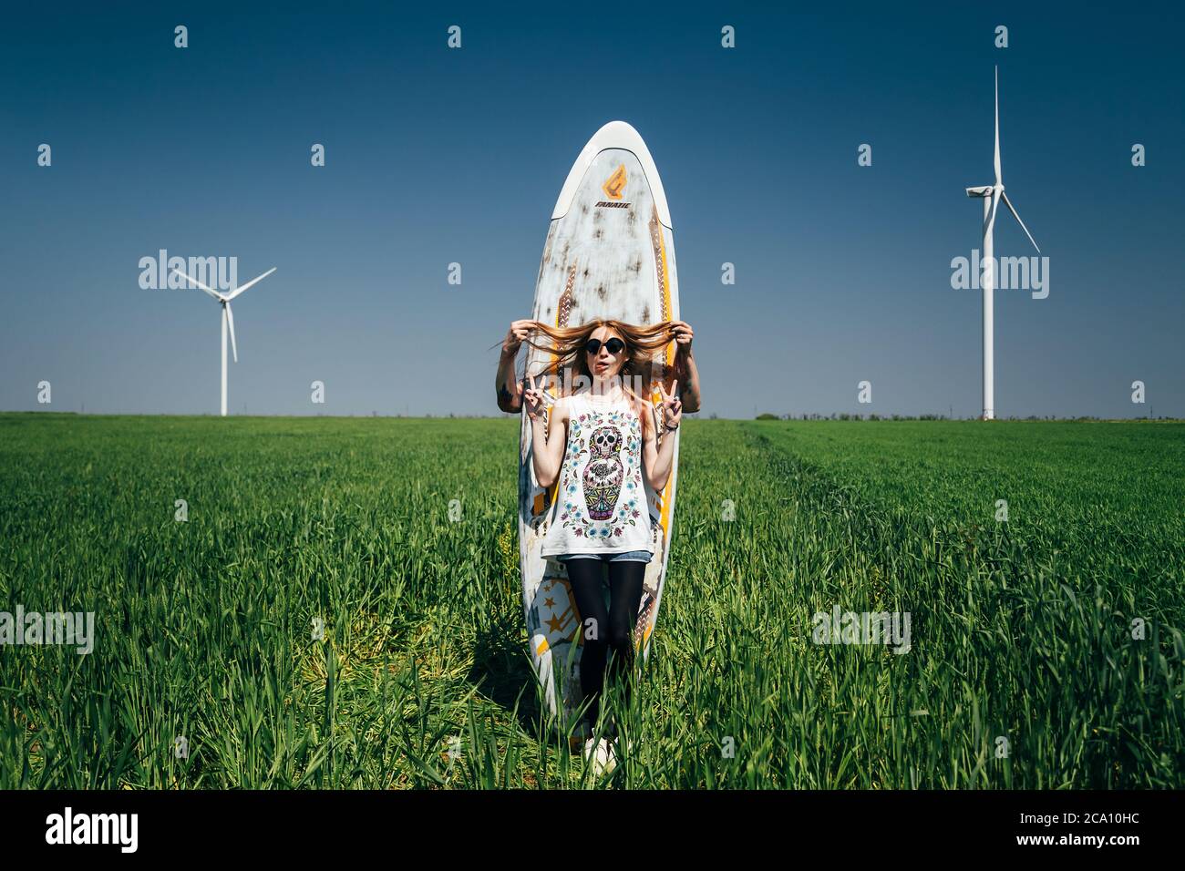 ODESSA, UKRAINE - MAI, 20 2015: Mignon jeune couple hippster plaisante au milieu du champ vert avec une planche de surf, heureux portrait en plein air Banque D'Images