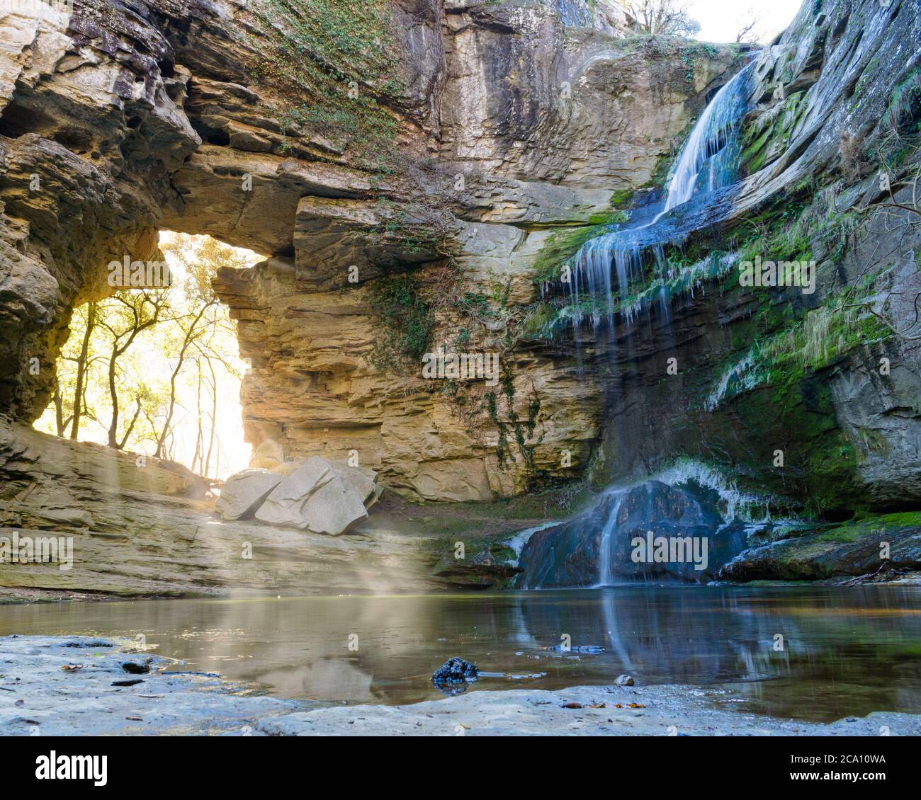 Endroit magique avec une chute d'eau et une entrée de lumière au milieu de la roche. Banque D'Images