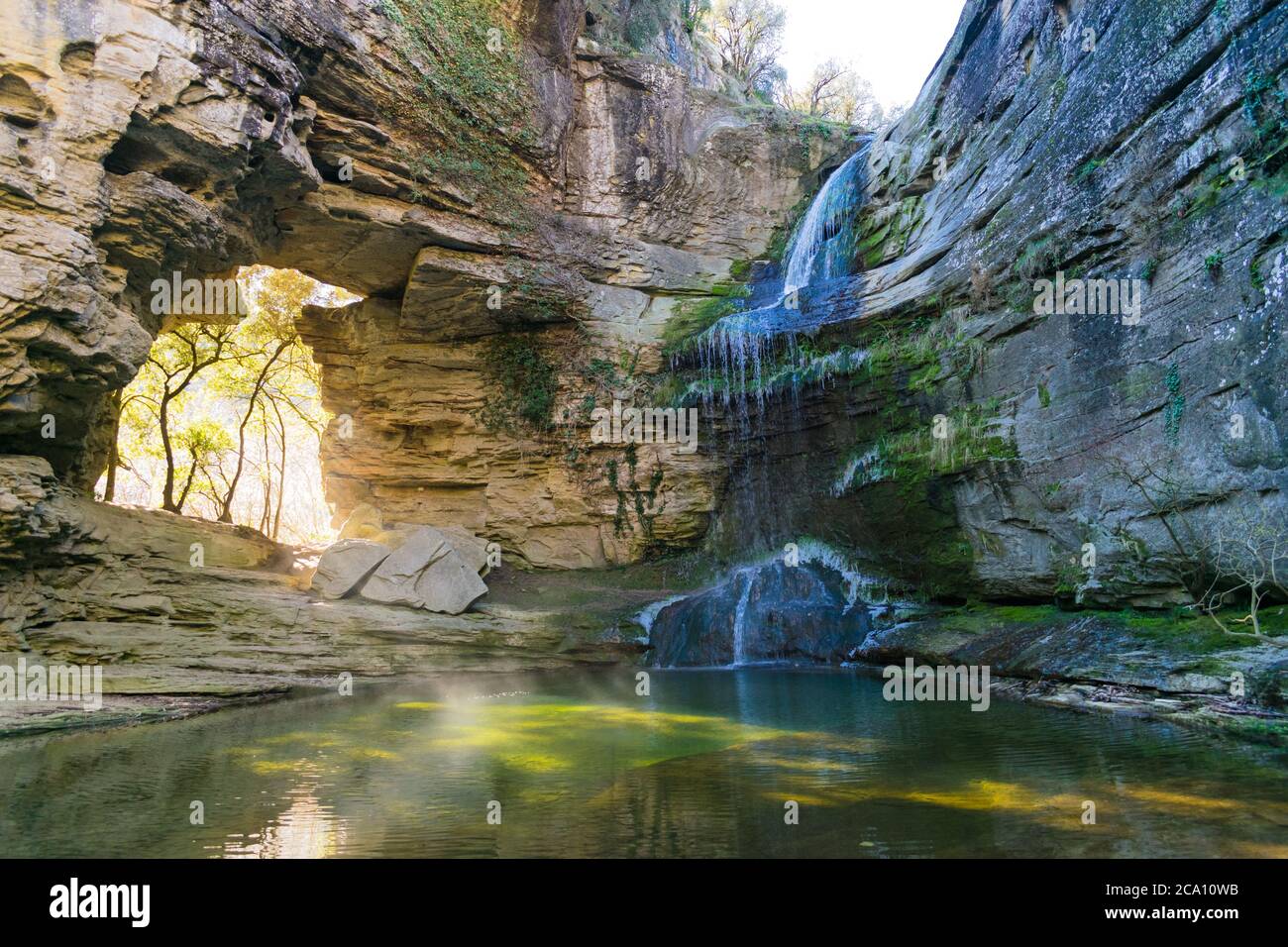 Endroit magique avec une chute d'eau et une entrée de lumière au milieu de la roche. Banque D'Images