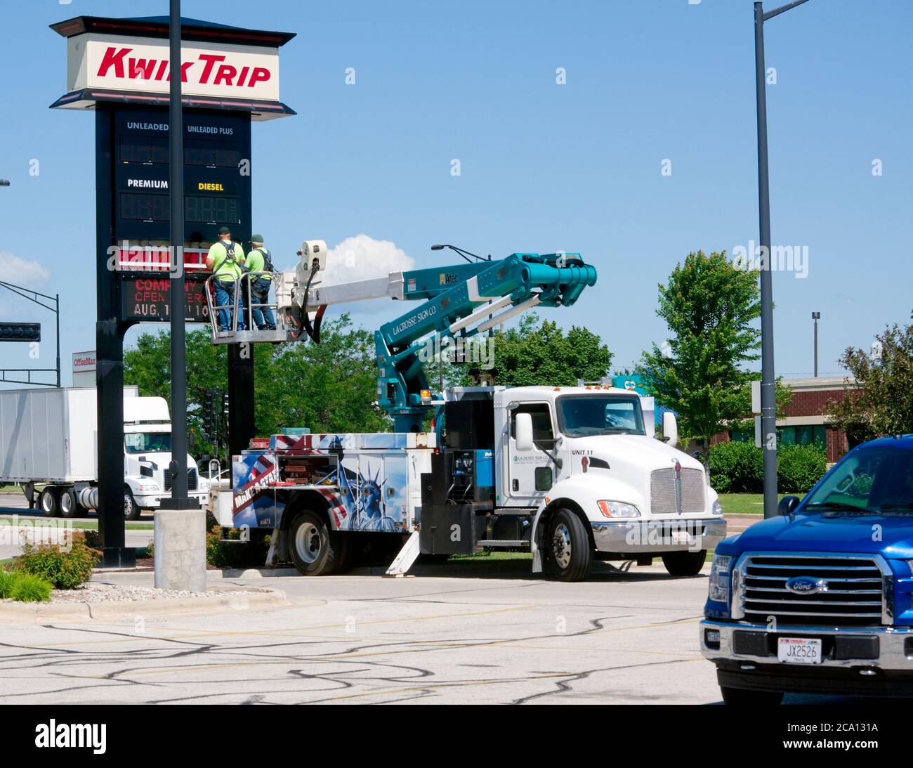 Deux hommes installant l'affiche, travaillant à partir du camion Kenworth avec le godet de levage de flèche Altec. Banque D'Images