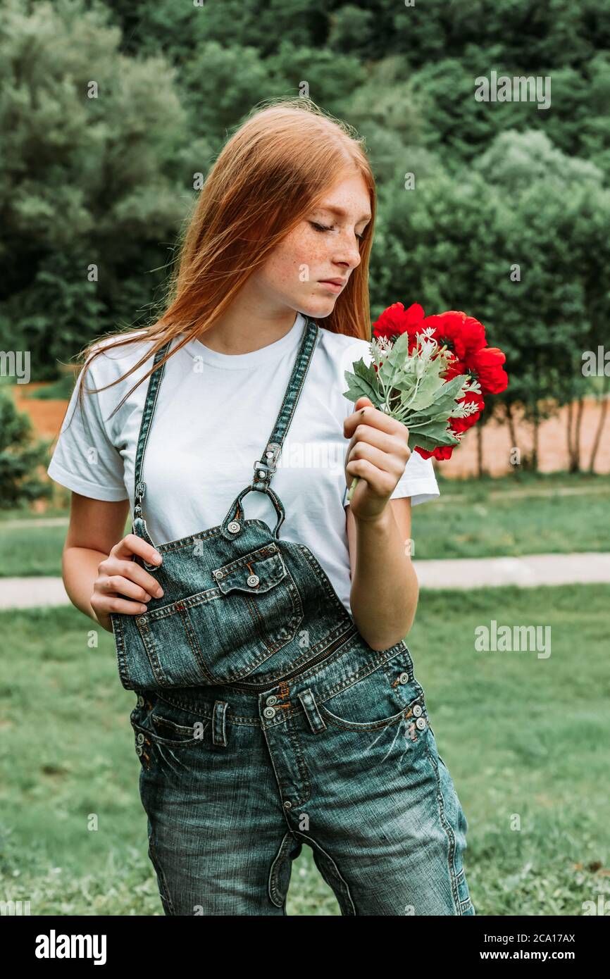 Portrait d'une jeune fille de gingembre à taches de rousseur tenant un bouquet de roses Banque D'Images