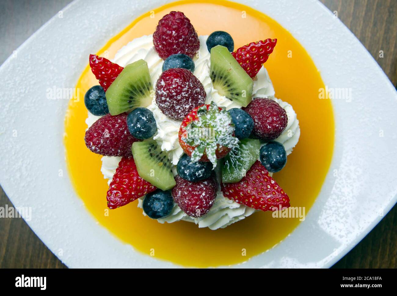 Fruits mélangés avec meringue, crème et coulis d'orange Banque D'Images