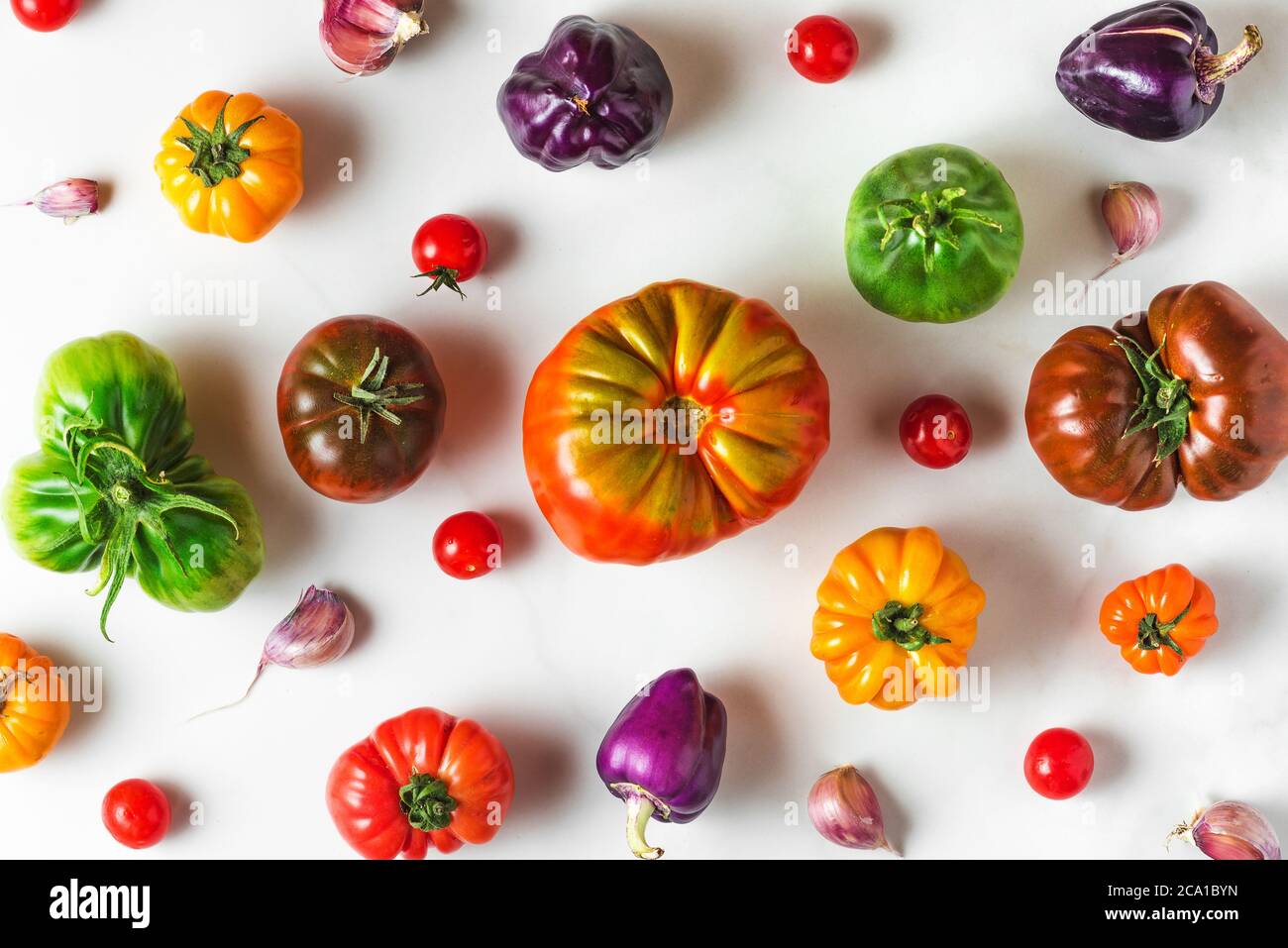 composition des aliments. différentes tomates biologiques colorées et légumes au poivre sur fond blanc. vue du dessus. plat Banque D'Images