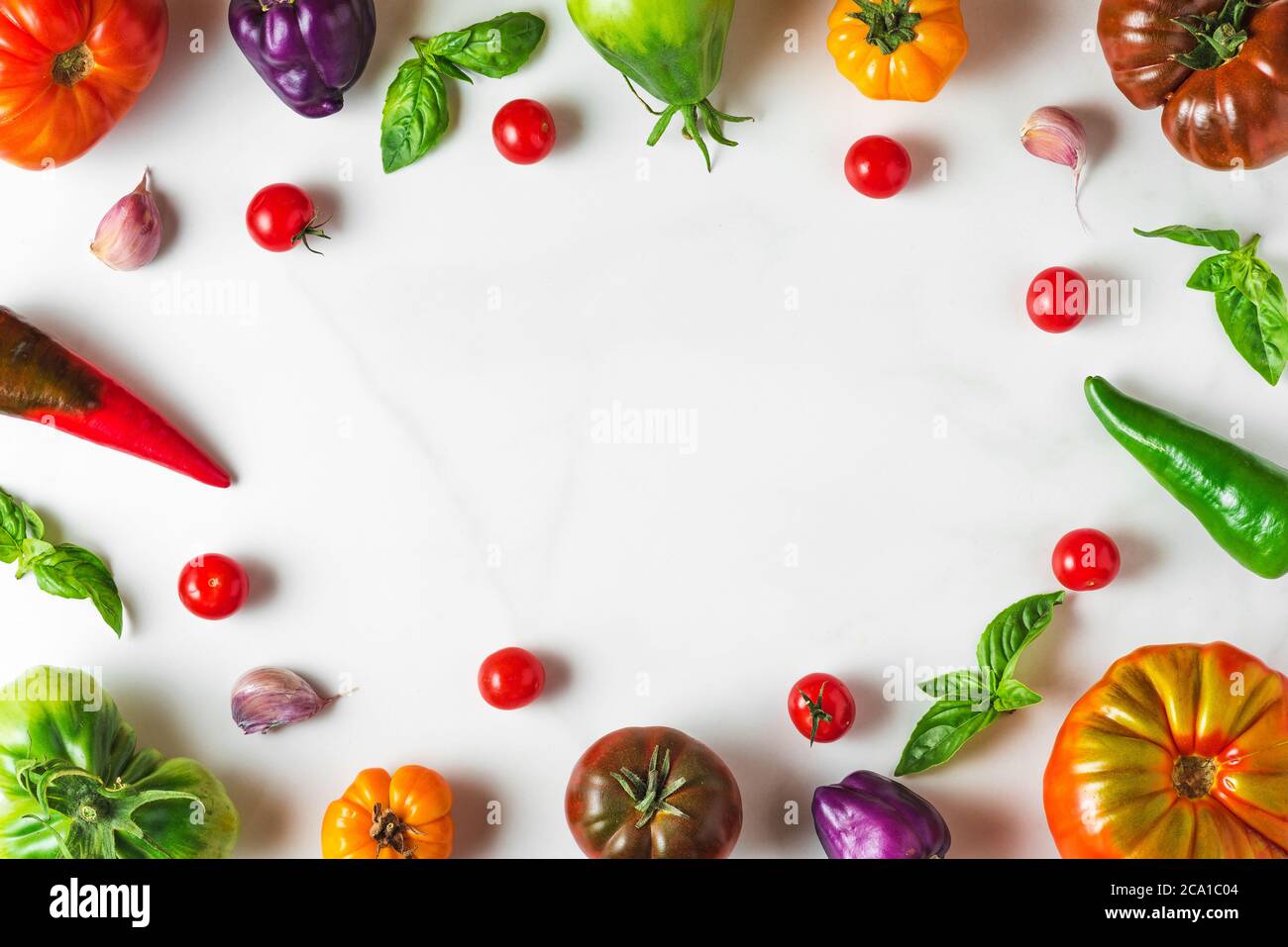 composition des aliments. cadre fait de légumes biologiques colorés. tomates, poivre, ail et basilic sur fond blanc. vue du dessus avec espace copie. flat la Banque D'Images