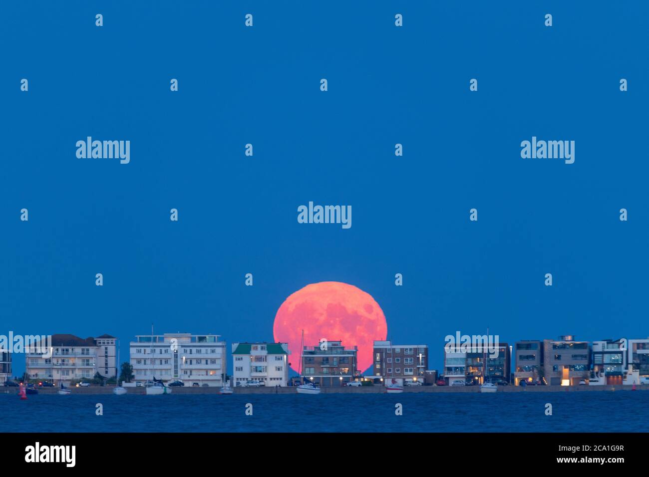 La pleine lune d'août ('sturgeon') s'élève au-dessus du célèbre Millionaire's Row à Sandbanks à Poole, Dorset. Banque D'Images