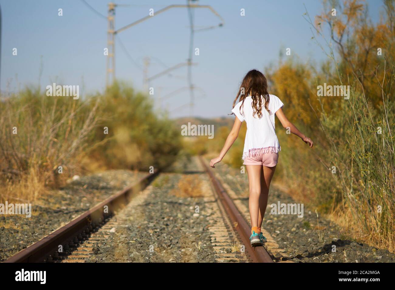 fille jouant l'équilibrage sur une piste de train abandonnée dans le champ Banque D'Images