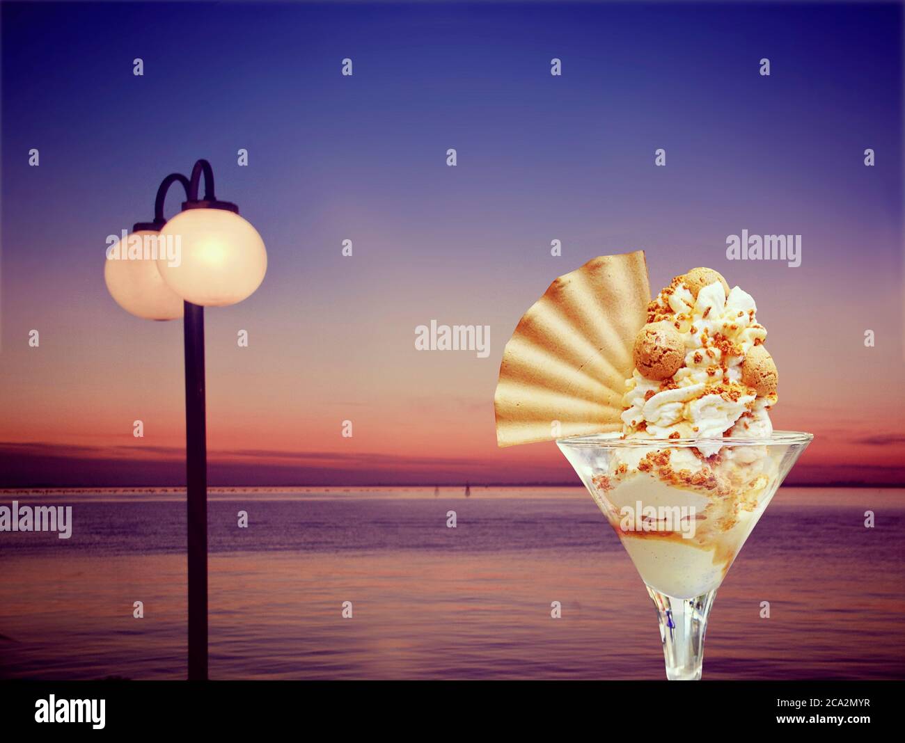 Nuit d'été au café de la promenade de la mer en dégustant une glace sundae surmontée de crème fouettée, d'amaretti et de gaufres Banque D'Images