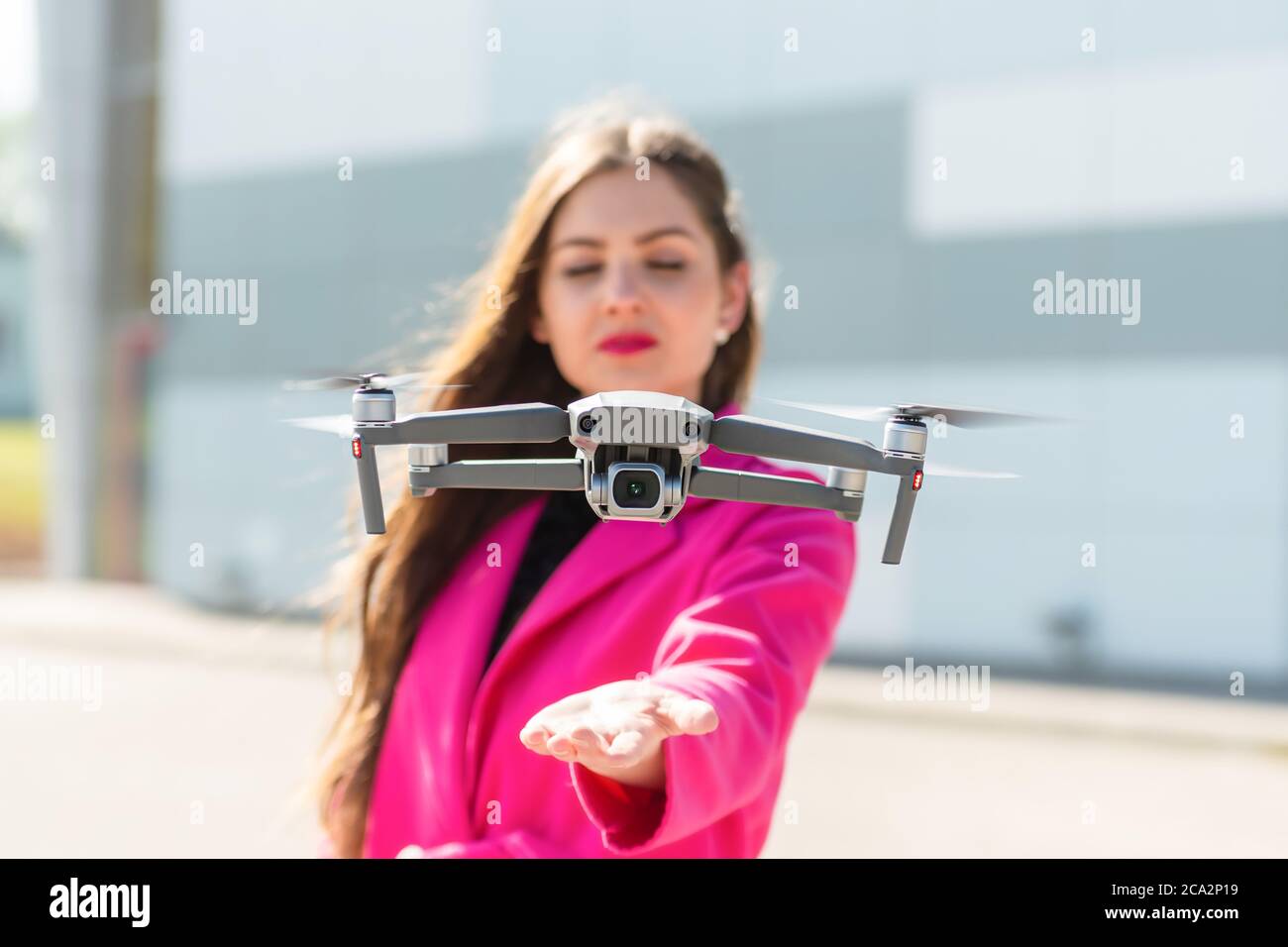 des terrains de drone sur la main, jeune femme défoqué en arrière-plan, se concentrent sur le quadricoptère Banque D'Images