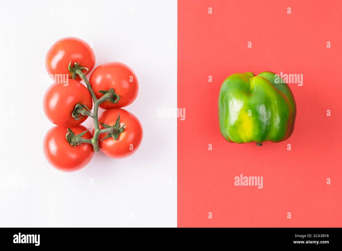 Mise en page créative au poivre et à la tomate sur fond rouge et blanc coloré. Banque D'Images