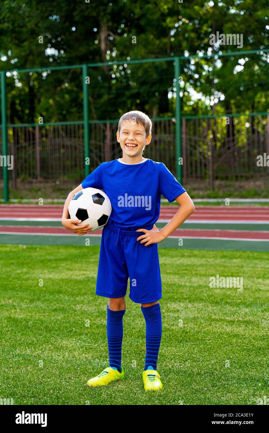 un petit joueur de football avec un ballon se tient sur un terrain de  football vert Photo Stock - Alamy