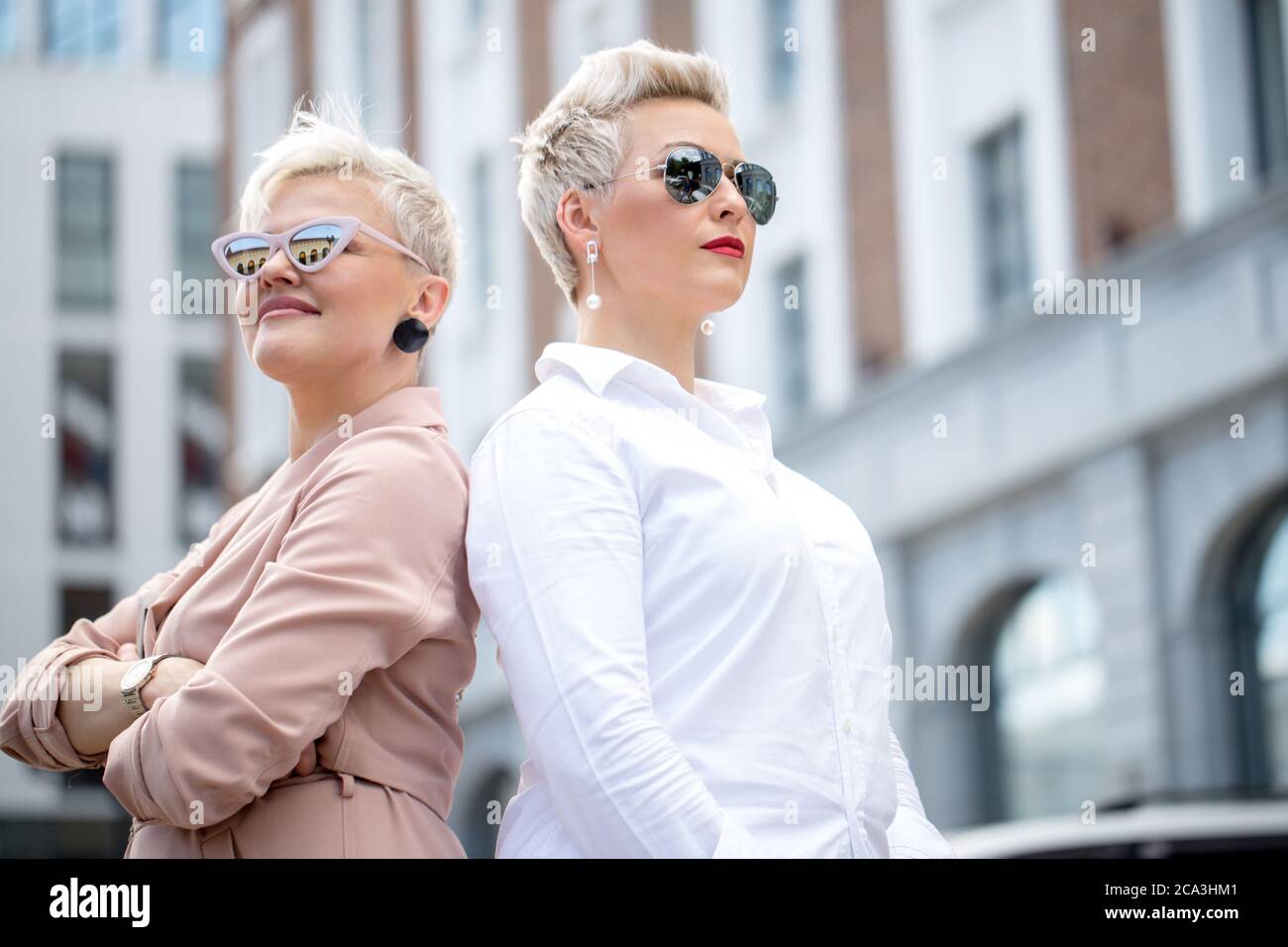 Deux dames en lunettes posant dehors office building Banque D'Images