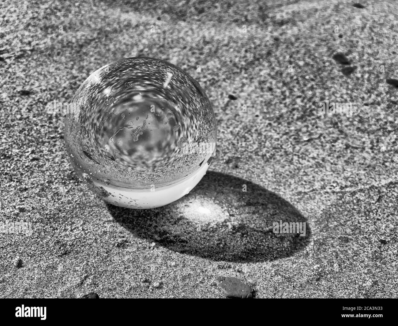 Boule transparente sur la plage avec reflets de sable. Banque D'Images