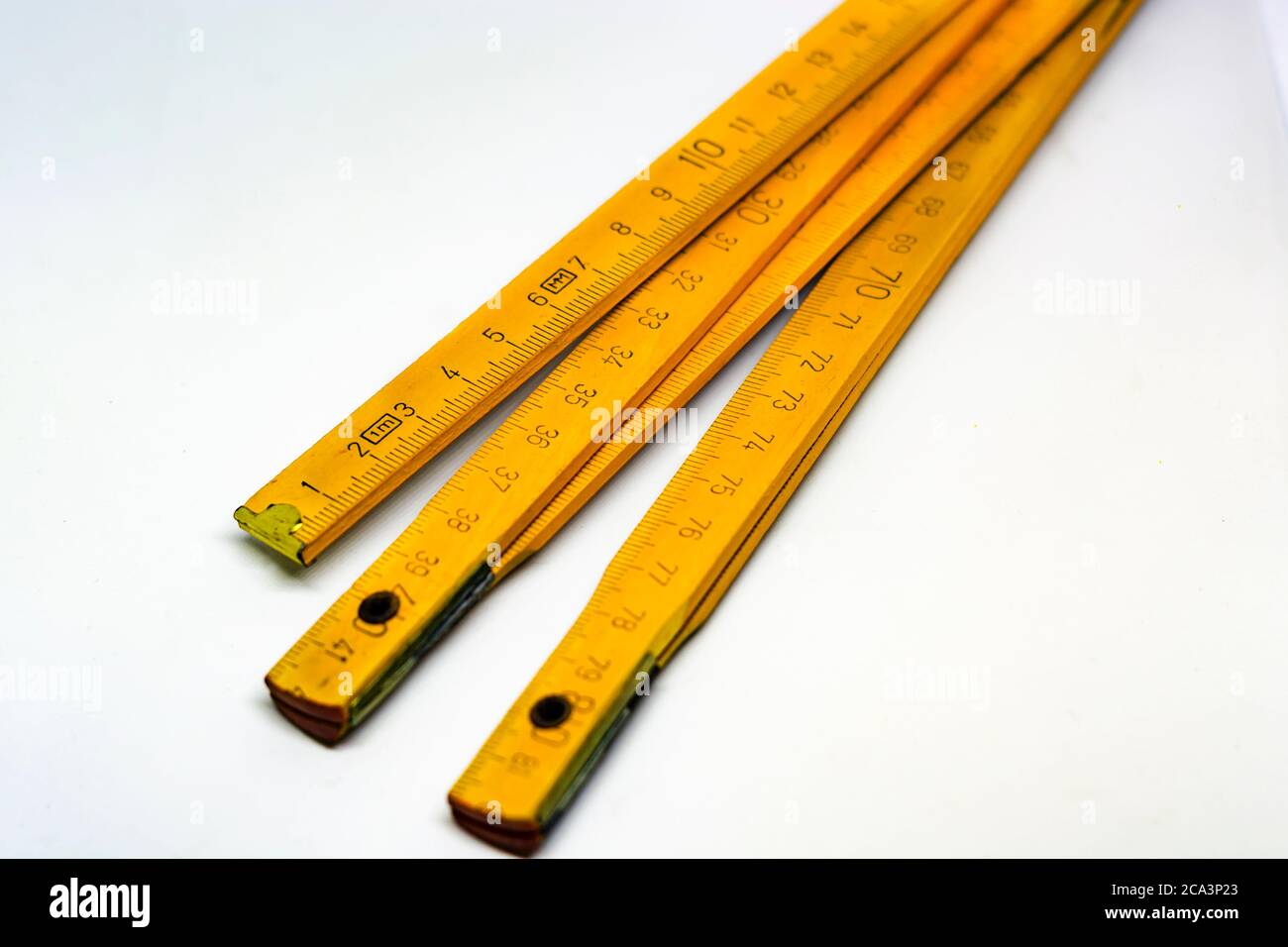 Mètre pliant en bois jaune avec extrémités en laiton isolées sur fond blanc. Entièrement étendu, il mesure 2 mètres. Instrument de mesure utilisé dans con Banque D'Images