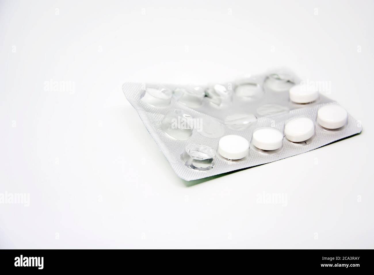 Un blister utilisé avec quelques pilules manquantes isolé sur un fond blanc. Médicaments et produits pharmaceutiques. Banque D'Images