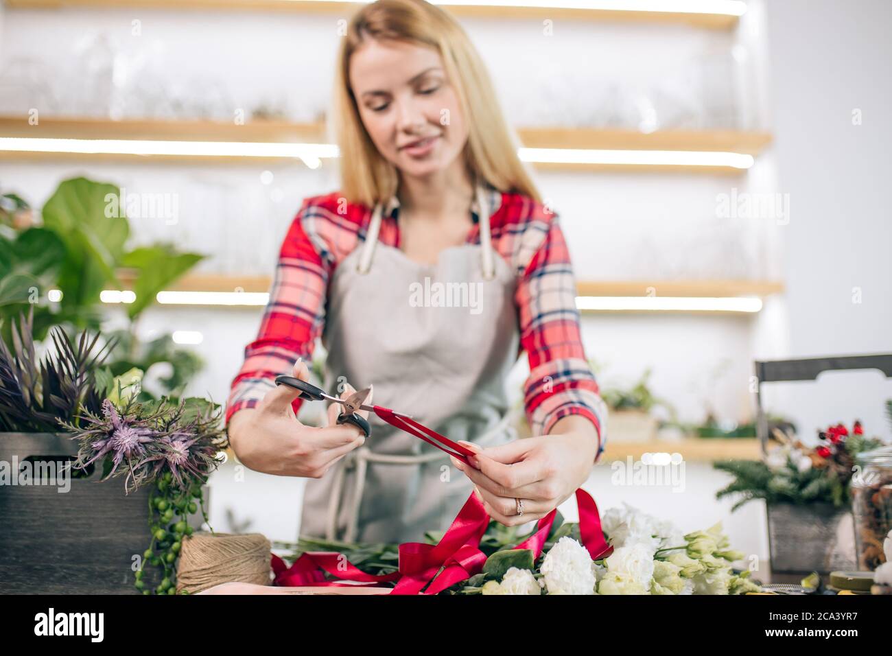 jeune femme caucasienne aux cheveux blonds aiment travailler comme fleuriste, propriétaire attrayant de magasin, jeune jardinier autour des plantes prennent soin des fleurs Banque D'Images
