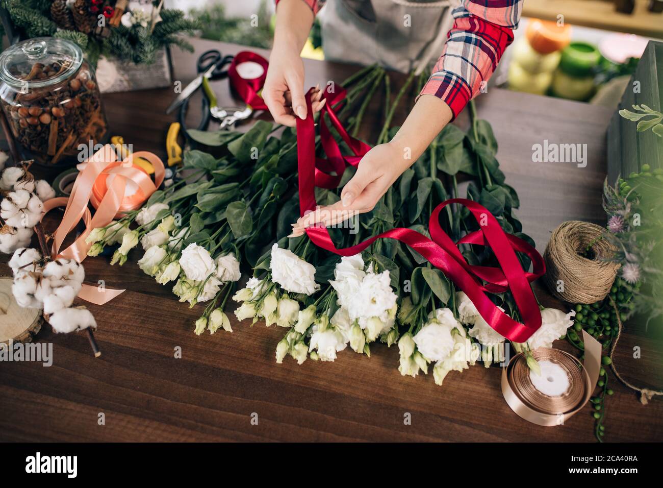 culture soigneuse floristerie, composition bouquet de belles roses blanches  pour la clientèle dans son propre magasin, ruban rouge sur les fleurs.  plantes, fleurs, décor Photo Stock - Alamy