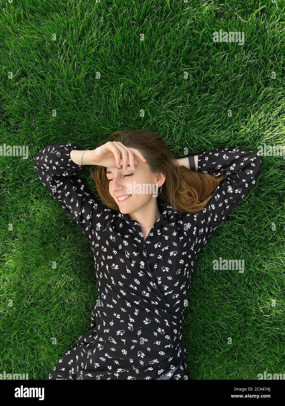 Jeune fille qui pose dans l'herbe et sourire Banque D'Images