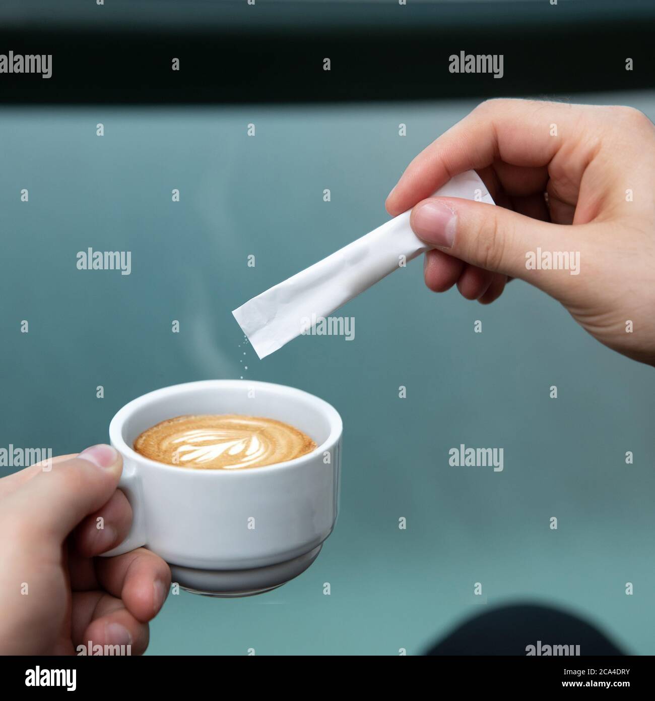 Homme versant du sucre dans le café latte Banque D'Images