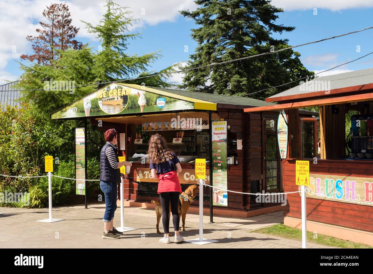 Femmes à l'extérieur d'un kiosque de crème glacée de café avec des signes sociaux de distanciation pendant la pandémie Covid-19. Symonds Yat West Forest of Dean Herefordshire, Angleterre, Royaume-Uni Banque D'Images