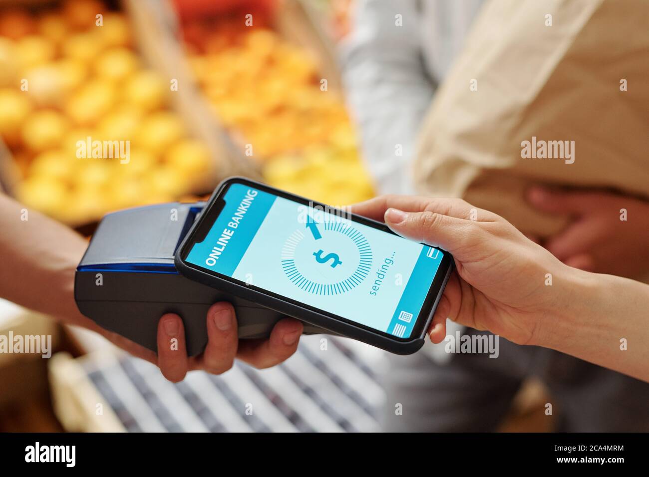 Gros plan sur une femme méconnue qui met un smartphone au terminal tout en payant des produits en ligne sur le marché alimentaire Banque D'Images