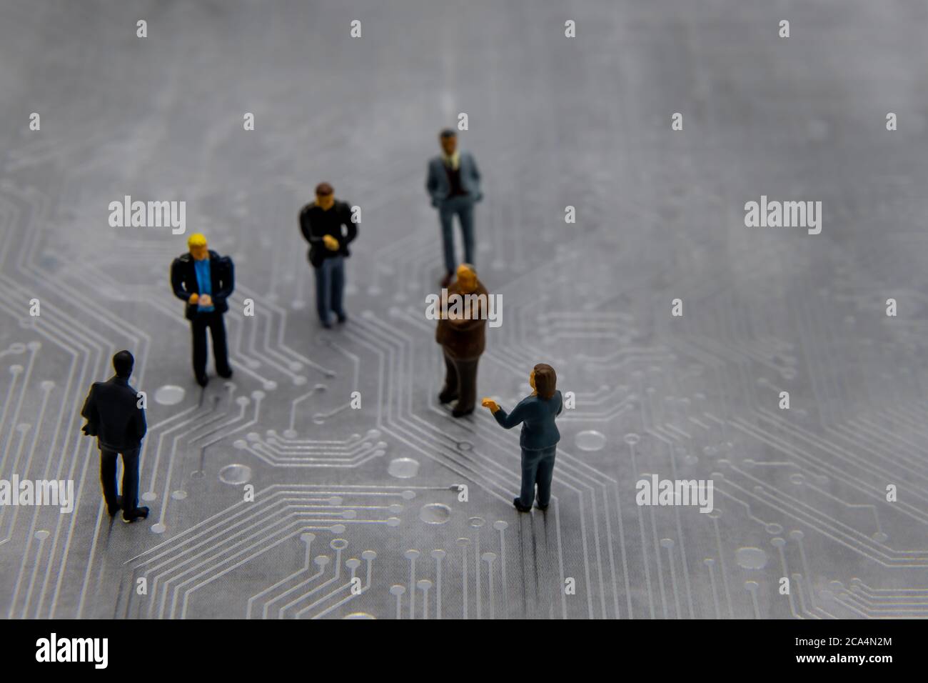 Figurines miniatures posées en tant que gens d'affaires dans une réunion sur le circuit imprimé futuriste abstrait, futur concept d'affaires Banque D'Images