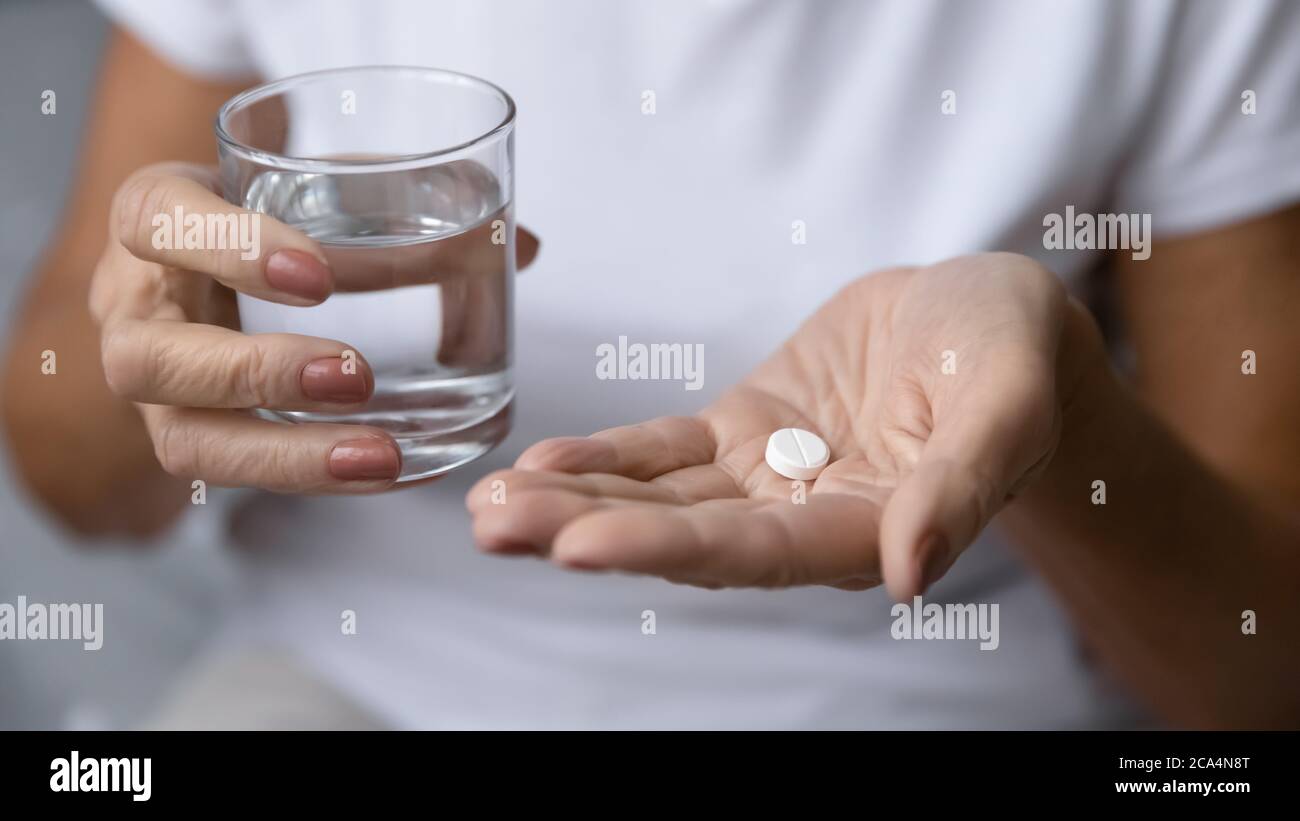 Gros plan femme mature mains tenant la pilule et le verre d'eau Banque D'Images