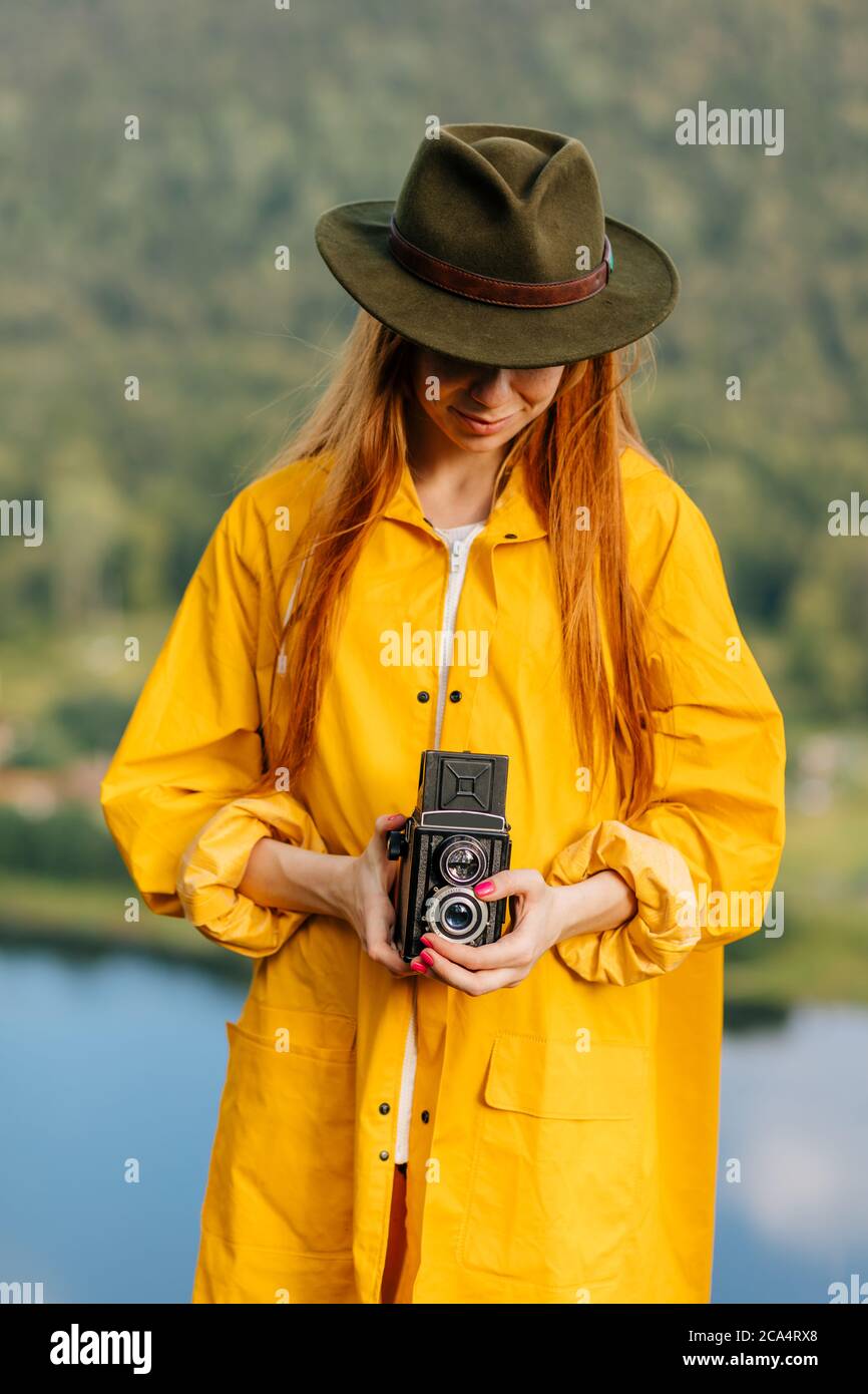 randonneur attrayant en imperméable jaune et chapeau vert en utilisant son  appareil photo pendant la randonnée.voyage, photo de gros plan,  passe-temps, passe-temps, intérêt Photo Stock - Alamy