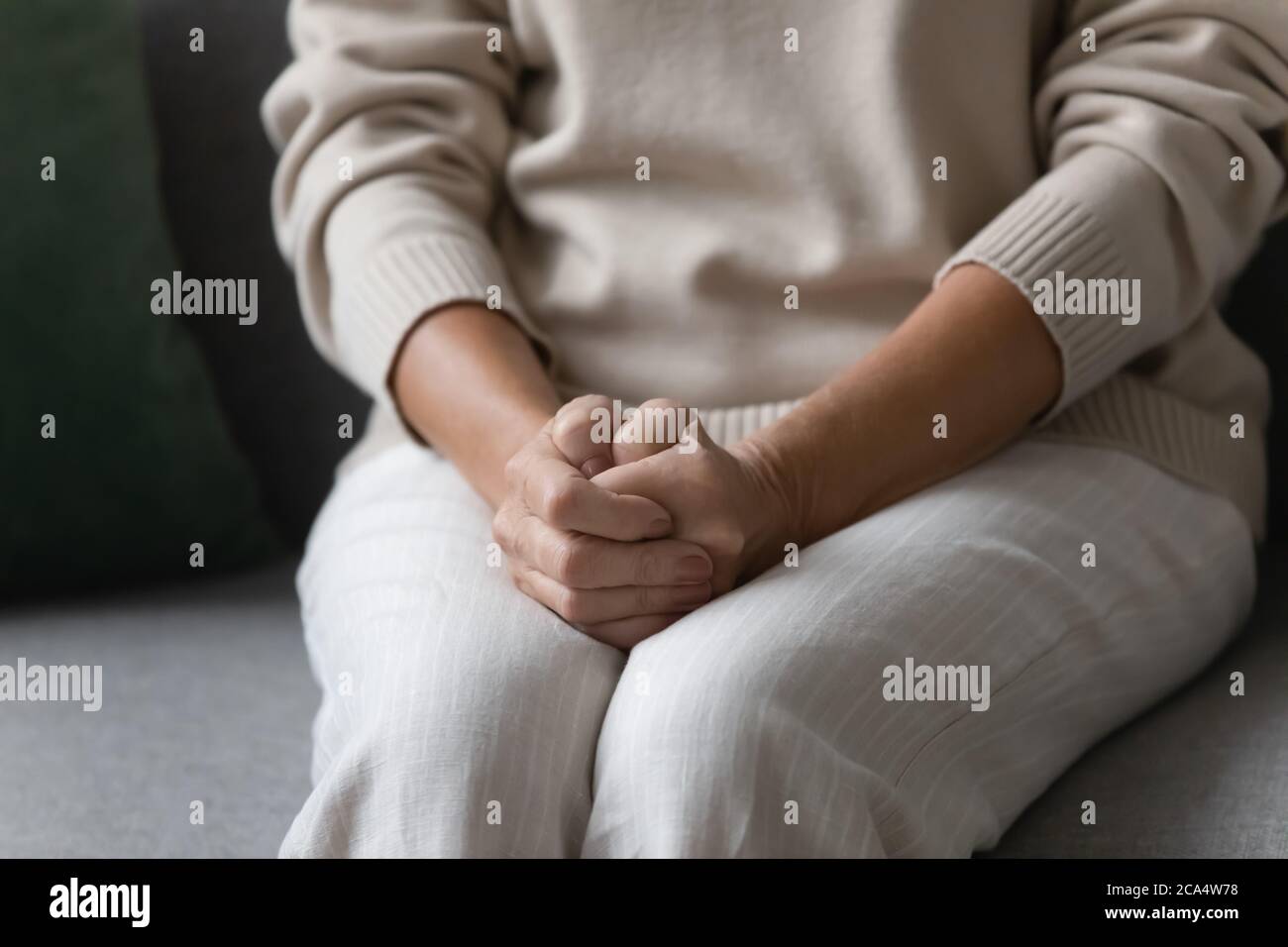 Une femme solitaire âgée a mis la main sur des tours assis sur un canapé Banque D'Images