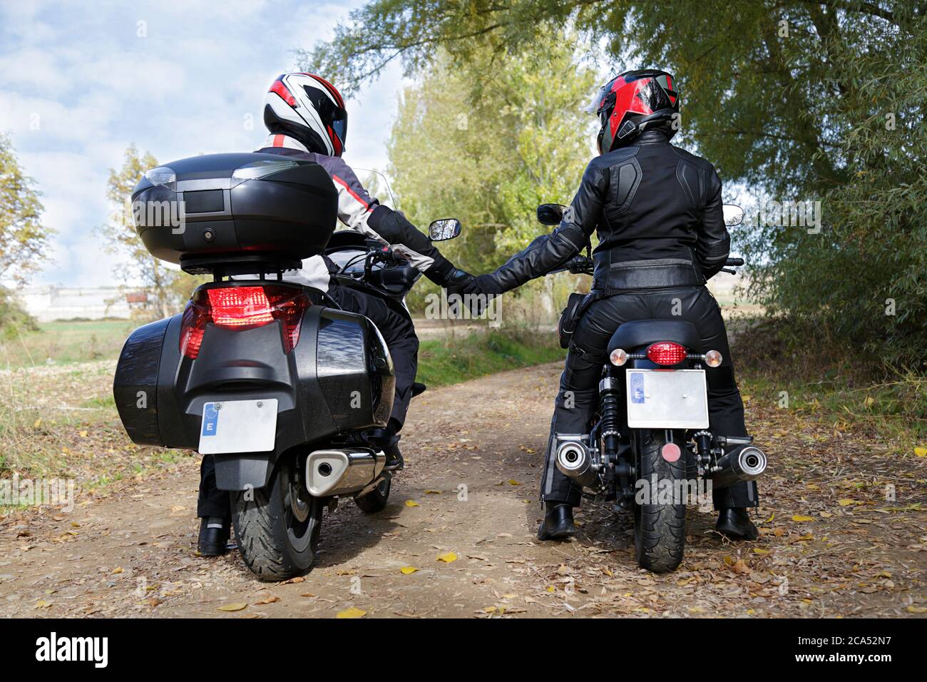 Deux motocyclistes se tenant les mains tout en étant assis sur des motos Banque D'Images