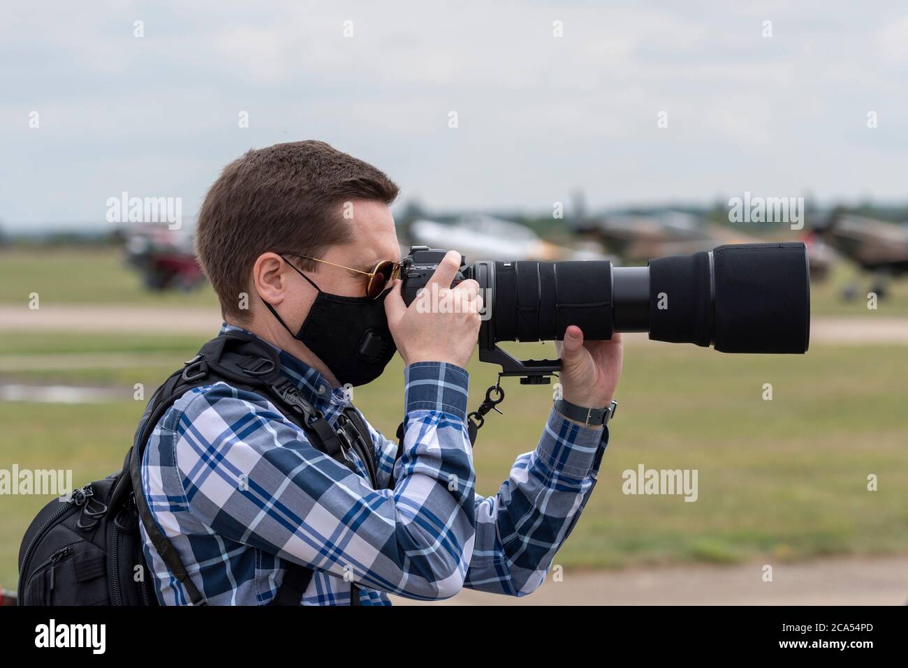 Imperial War Museum Duxford, Cambridgeshire, Royaume-Uni. 4 août 2020. Après une longue période de fermeture due à l'enfermement du coronavirus COVID-19, le musée a rouvert ses portes aux visiteurs le 1er août. Aujourd'hui, le musée a tenu son premier événement d'exposition aérienne, intitulé a Showcase Day. Il s'agissait d'un événement réservé à l'avance avec une limite de visiteurs considérablement réduite, et le public en visite devait se conformer à des directives strictes lors de l'entrée dans les expositions intérieures. Un photographe avec un objectif zoom long et un masque facial Banque D'Images