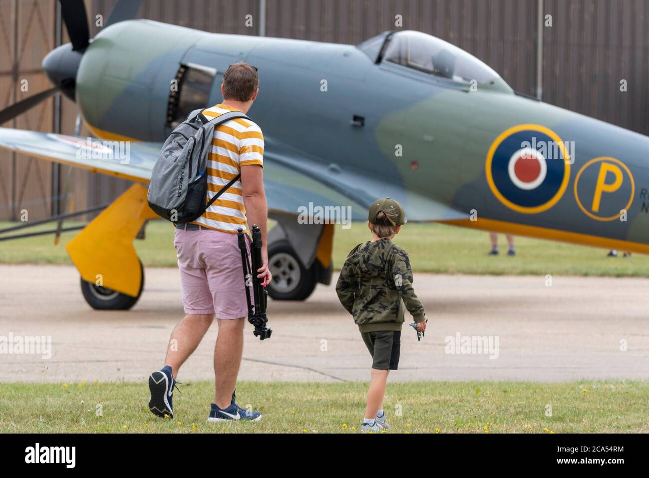 Imperial War Museum Duxford, Cambridgeshire, Royaume-Uni. 4 août 2020. Après une longue période de fermeture due à l'enfermement du coronavirus COVID-19, le musée a rouvert ses portes aux visiteurs le 1er août. Aujourd'hui, le musée a tenu son premier événement d'exposition aérienne, intitulé a Showcase Day. Il s'agissait d'un événement réservé à l'avance avec une limite de visiteurs considérablement réduite, et le public en visite devait se conformer à des directives strictes lors de l'entrée dans les expositions intérieures. Père et fils regardant un avion de chasse Hawker Fury de la Seconde Guerre mondiale Banque D'Images