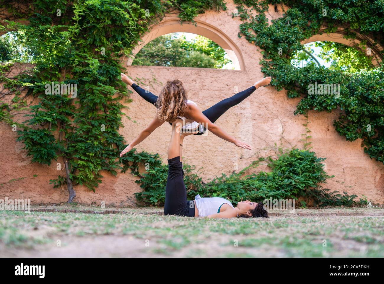 Deux belles femmes faisant acroyoga dans le jardin ou le parc Banque D'Images