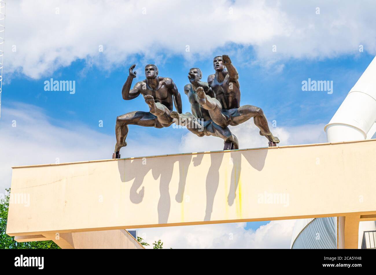 Minsk, Bélarus, 26 juillet 2020 : sculpture en cours avec des hommes, monument aux coureurs au-dessus de l'entrée du stade olympique national de Dinamo dans le centre historique de la ville de Minsk, ciel bleu, nuages blancs dans la journée ensoleillée d'été Banque D'Images