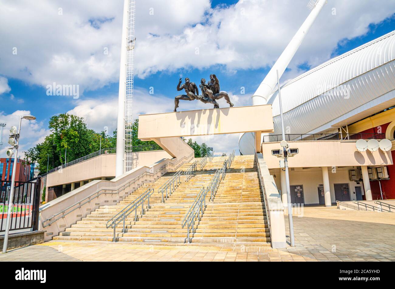 Minsk, Bélarus, 26 juillet 2020 : entrée au stade olympique national de Dinamo avec sculpture, monument et escalier des coureurs hommes en course dans le centre historique, ciel bleu, nuages blancs dans le soleil de l'été Banque D'Images