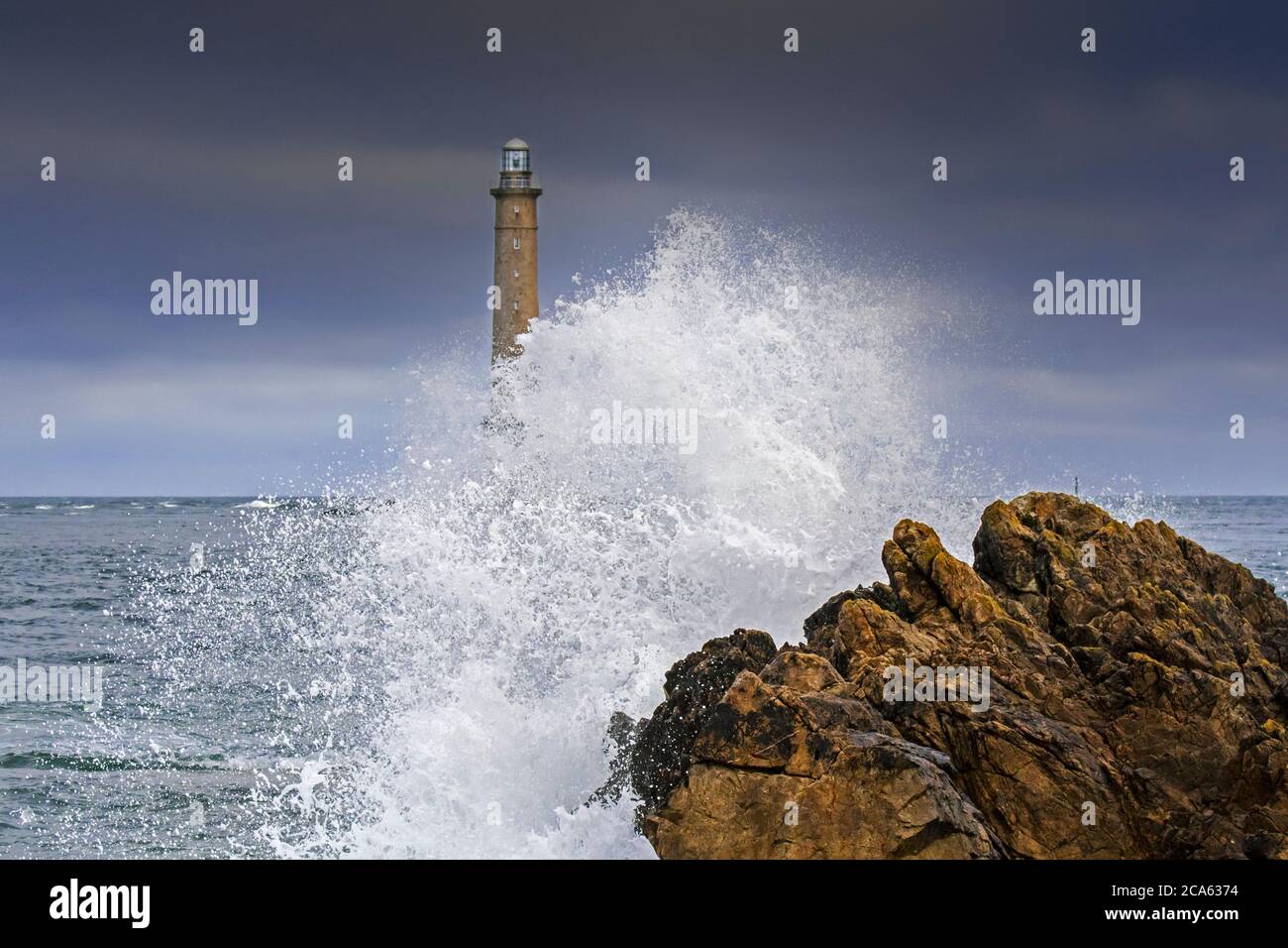 Les vagues s'écrasant sur le rocher et le phare Phare de la Hague / Phare de Goury près d'Auderville, Cap de la Hague, péninsule du Cotentin, Basse-Normandie, France Banque D'Images