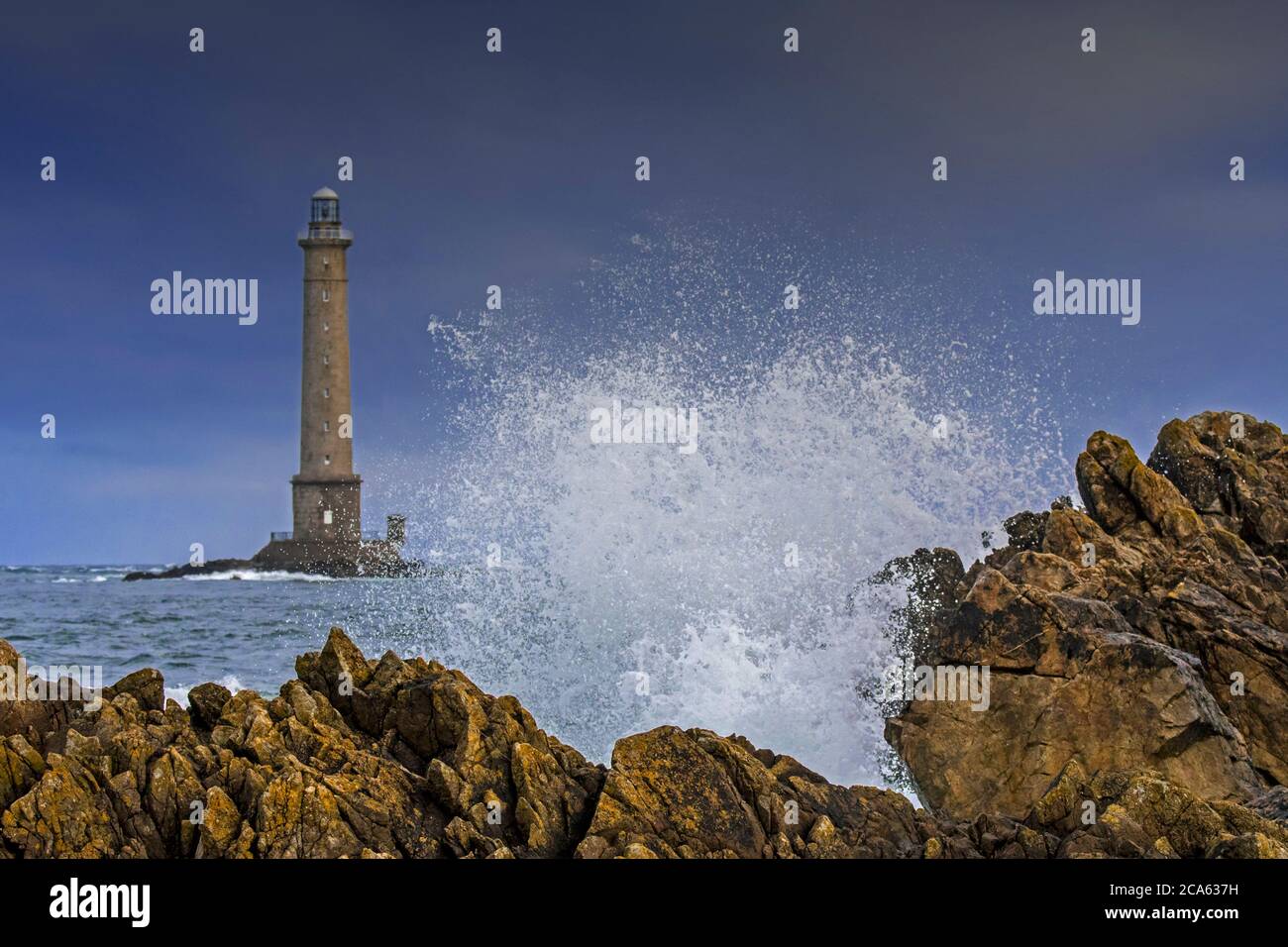 Les vagues s'écrasant sur le rocher et le phare Phare de la Hague / Phare de Goury près d'Auderville, Cap de la Hague, péninsule du Cotentin, Basse-Normandie, France Banque D'Images