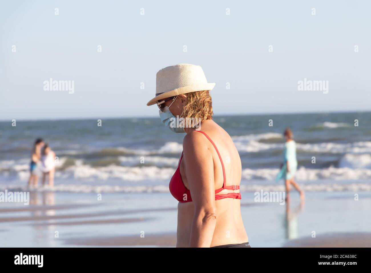 Punta Umbria, Huelva, Espagne - 2 août 2020 : femme marchant sur la plage et portant des masques protecteurs ou médicaux. Nouvelle normale en Espagne avec dis social Banque D'Images