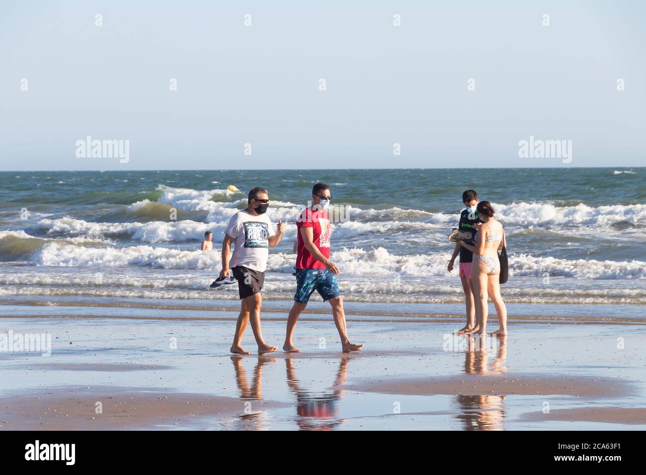 Punta Umbria, Huelva, Espagne - 2 août 2020 : deux hommes marchant sur la plage portant des masques protecteurs ou médicaux. Nouvelle normale en Espagne avec social d Banque D'Images